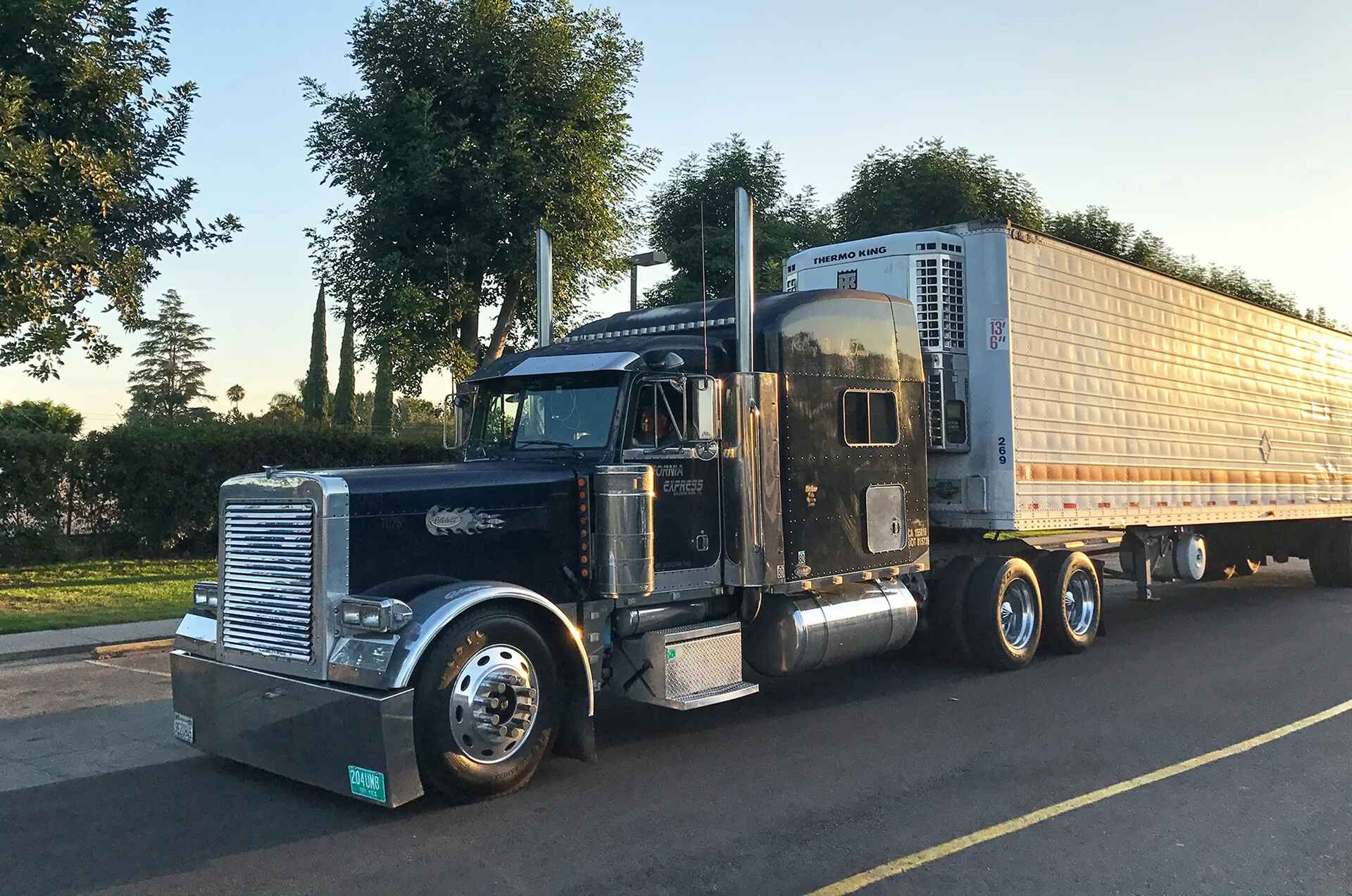 Semi truck traveling with freight on a road lined with trees